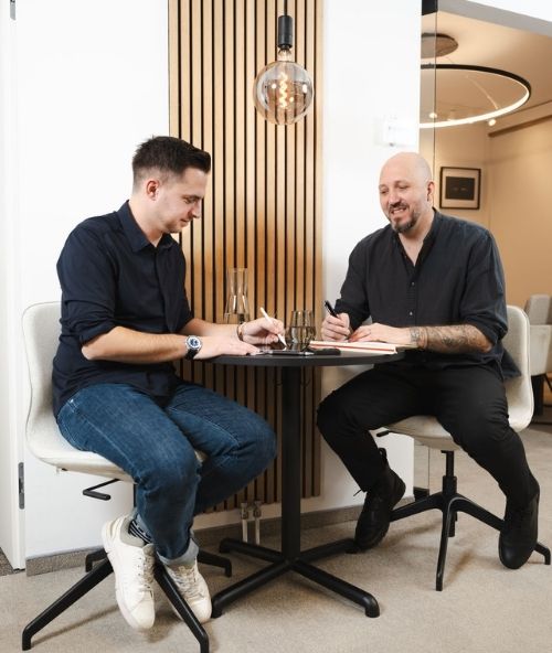 Das Team von BM Romar | Partner bei einer Projektbesprechung mit Bauplänen und Unterlagen am Tisch.